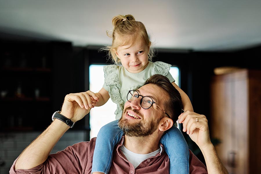 Photo of a father holding daughter on his shoulders